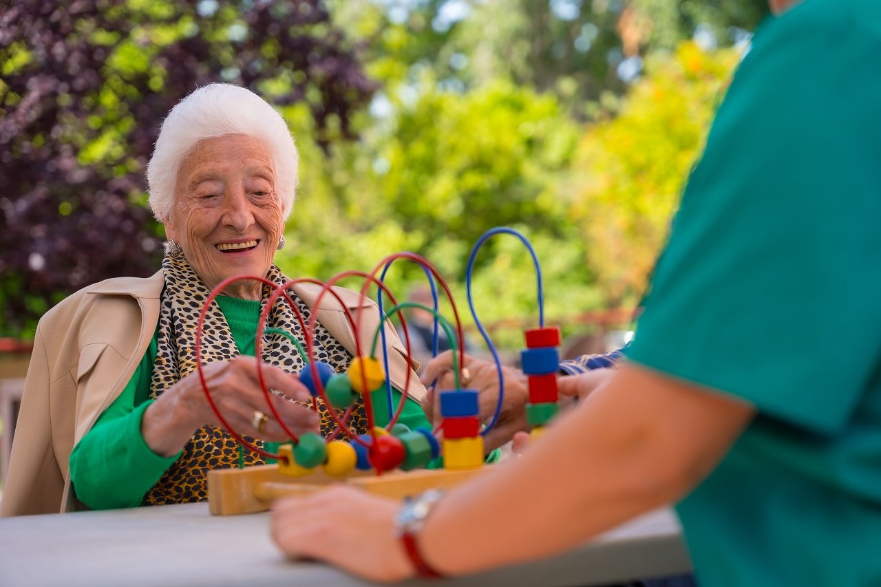 Hand of an elderly woman in the garden of a nursing home or retirement home playing with games to improve the mobility of the hands smiling